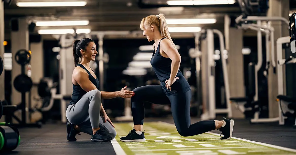 Modern gym with fitness equipment and personal trainers working with clients